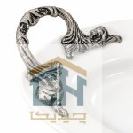 جزئیات نزدیک دسته پیوتر نقره ای رنگ با نقوش برجسته روی لبه دیس چینی سفید